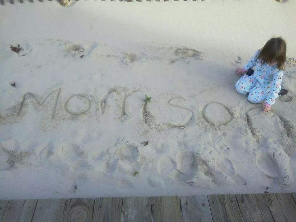 A Child Sitting In The Sand Writing On The Sand